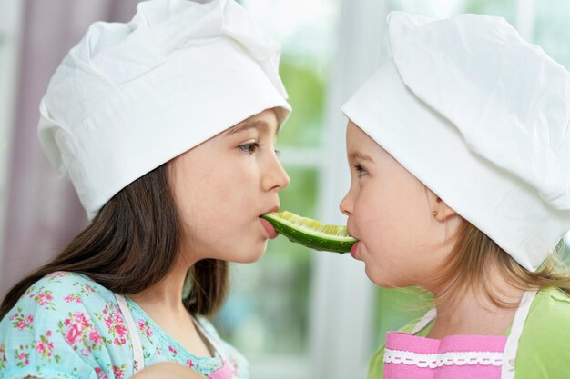 Ritratto di ragazze carine con cetriolo in cucina