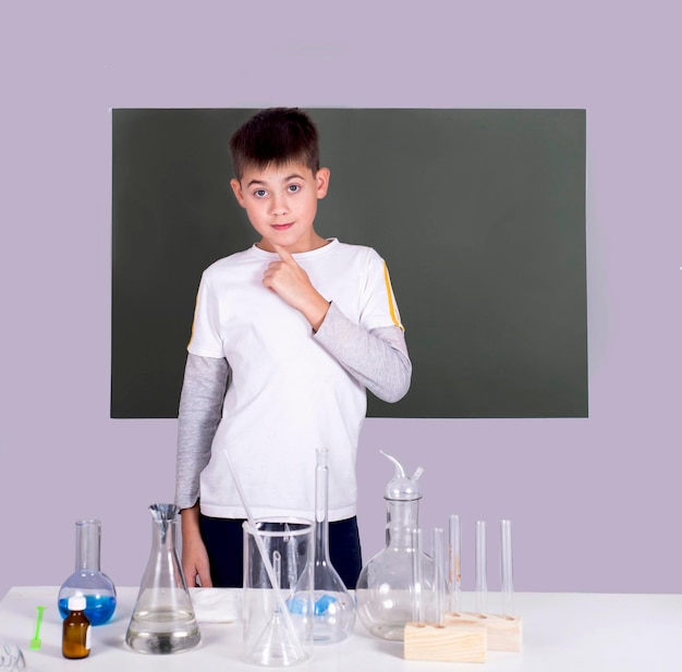 Ritratto di ragazzino che fa esperimenti chimici con liquido multicolore in provette
