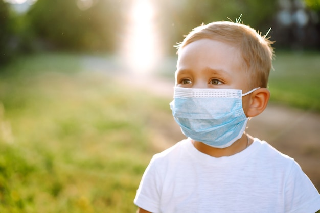 Ritratto di ragazzino con maschera medica nel parco.