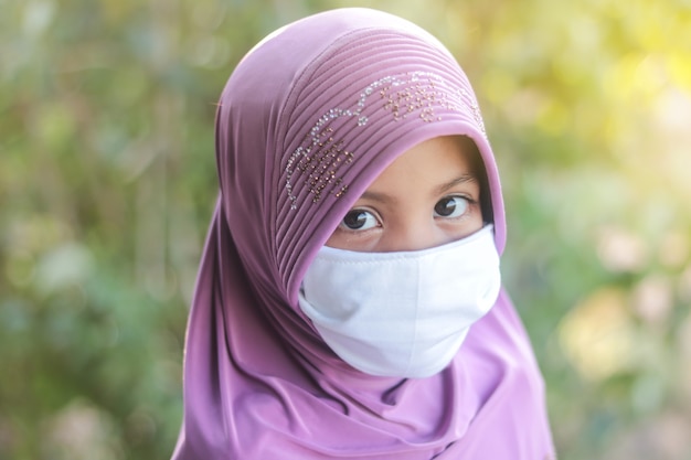 Ritratto di ragazzino musulmano con maschera da portare hijab. Concetto di Covid-19 o Coronavirus.