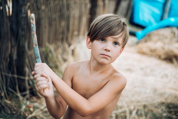 Ritratto di ragazzo allegro sdraiato nel fieno, il ragazzo pubblicizza i vestiti per bambini per l'autunno felice