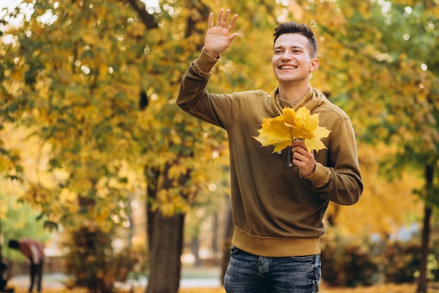 Ritratto di ragazzo bello e felice, sorridente e saluto nella sosta di autunno