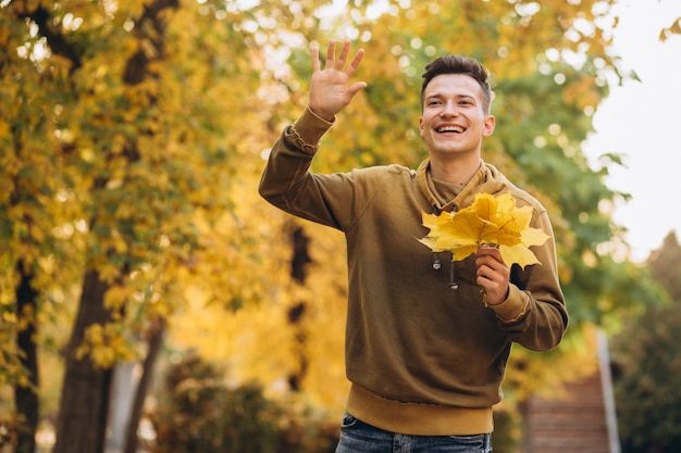 Ritratto di ragazzo bello e felice, sorridente e saluto nella sosta di autunno