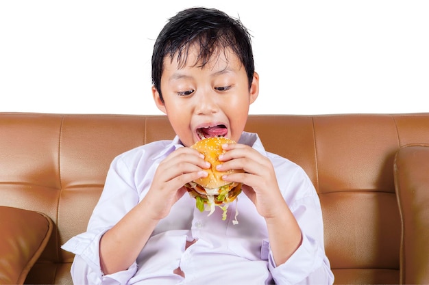 Ritratto di ragazzo che mangia un gustoso hamburger