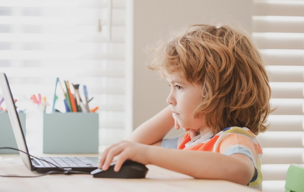 Ritratto di ragazzo della scuola che guarda il computer portatile durante la lezione Istruzione e apprendimento per il bambino