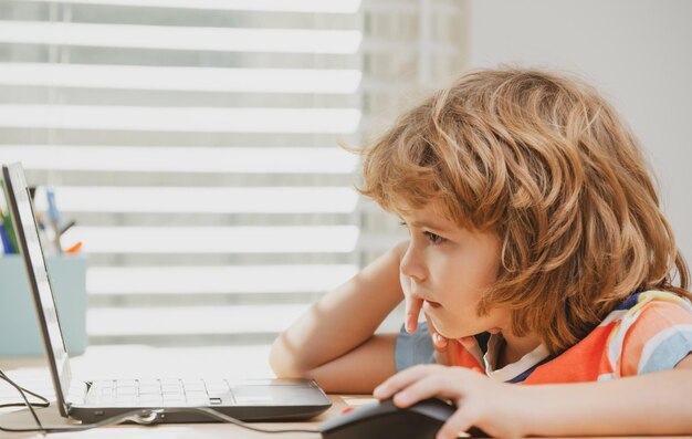 Ritratto di ragazzo di scuola che guarda il computer portatile durante la lezione il primo giorno a scuola carino bambino stu