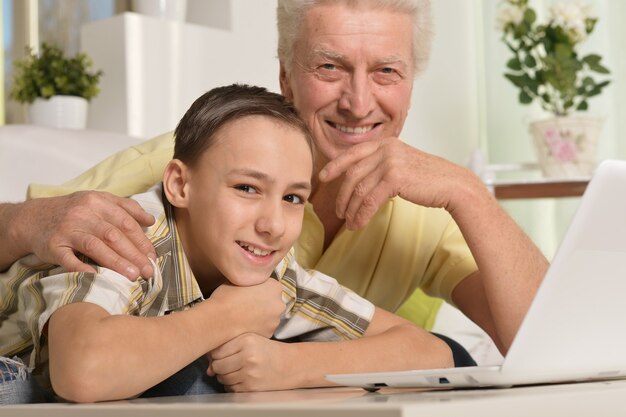 Ritratto di ragazzo e nonno con un laptop a casa