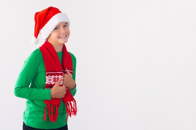 Ritratto di ragazzo felice che indossa il cappello di Babbo Natale e la sciarpa invernale Tempo di buon Natale