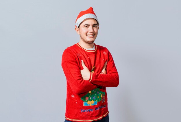 Ritratto di ragazzo in maglione e cappello di Natale con le braccia incrociate isolate Ragazzo sorridente con cappello di Natale con le braccia incrociate sorridente Ragazzo adolescente in abiti natalizi con le braccia incrociate sorridente