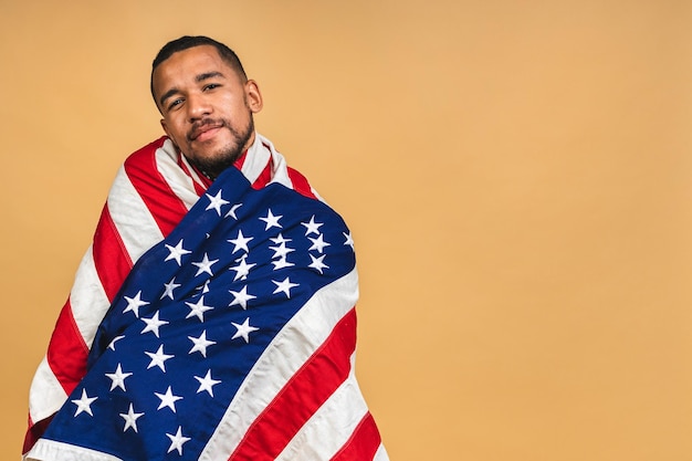 Ritratto di ragazzo nero afroamericano positivo che tiene bandiera usa isolata su sfondo beige