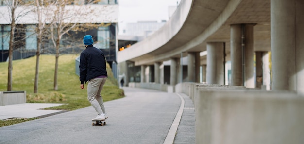 Ritratto di ragazzo pattinatore attivo in equilibrio su skateboard su sfondo urbano Spazio di copia banner
