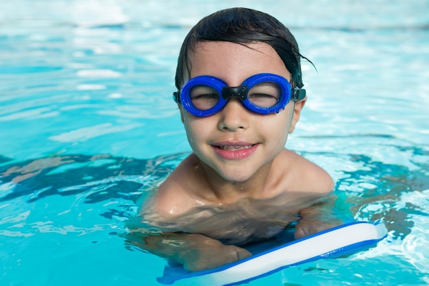 Ritratto di ragazzo sorridente con occhiali da nuoto nuotare in piscina