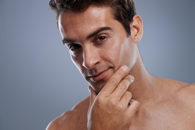 Ritratto di rasatura e uomo con cosmetici e dermatologia per la cura della pelle su uno sfondo grigio dello studio Viso di persona o modello con routine di pulizia o pelle sana con trattamento lucentezza o fiducia con luminosità
