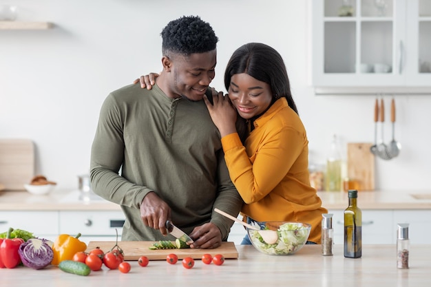Ritratto di romantici coniugi neri che preparano un pranzo sano a casa