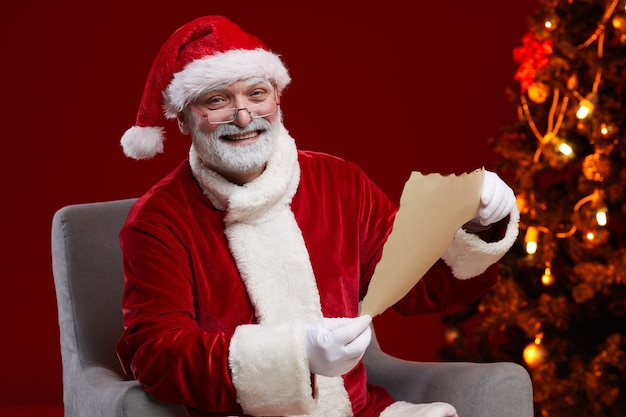 Ritratto di Santa sorridente mentre era seduto sulla poltrona e leggere la lettera di Natale
