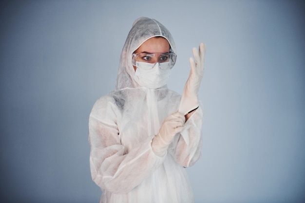 Ritratto di scienziata dottoressa in camice da laboratorio, occhiali difensivi e maschera indossando guanti