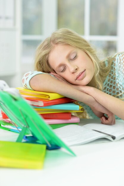 Ritratto di scolaretta stanca che dorme alla scrivania dopo aver studiato a casa
