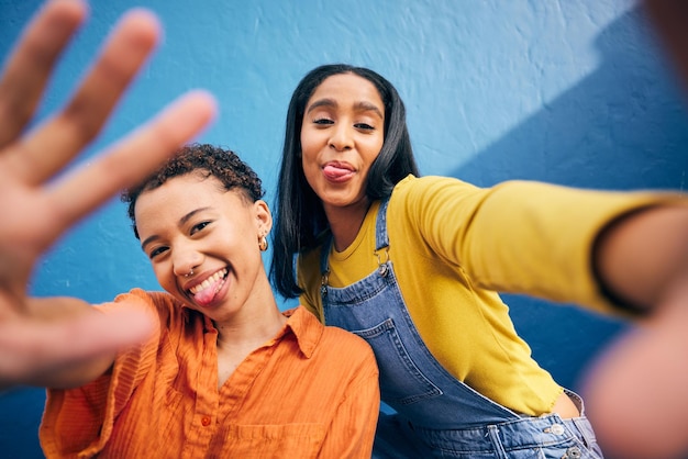 Ritratto di selfie comico e donne in città su sfondo blu per post sui social media e foto del profilo Sorriso di amicizia e persone di sesso femminile con la mano scattano foto per legare tempo di qualità e rilassarsi