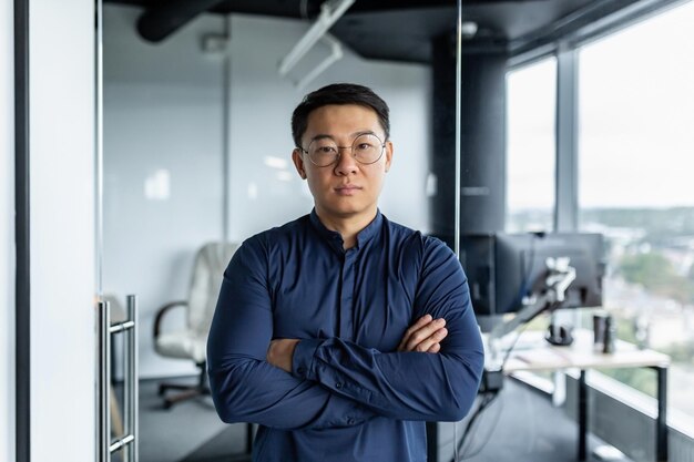 Ritratto di serio uomo d'affari sviluppatore asiatico con le braccia incrociate guardando concentrato verso l'uomo della fotocamera
