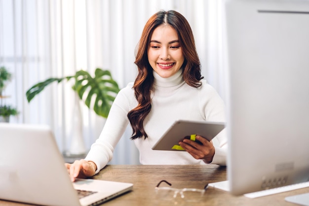 Ritratto di sorridente felice bella donna asiatica rilassante utilizzando la tecnologia del computer portatile mentre era seduto sul tavolo. Giovane ragazza creativa che lavora e digita sulla tastiera a casa. lavoro a casa concetto