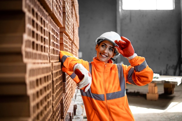 Ritratto di sorridente lavoratrice positiva in piedi nella fabbrica di produzione