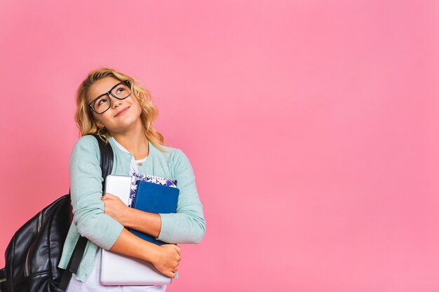 Ritratto di sorridente scuola ragazza bambino bambino con la borsa di scuola, laptop e libri, concetto di educazione.