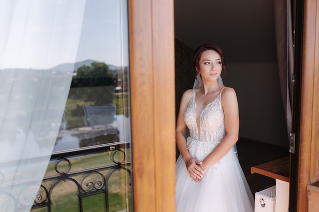 Ritratto di sposa elegante in abito da sposa moda stare sul balcone e in posa