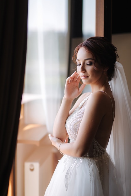 Ritratto di sposa elegante in abito da sposa moda stare sul balcone e in posa