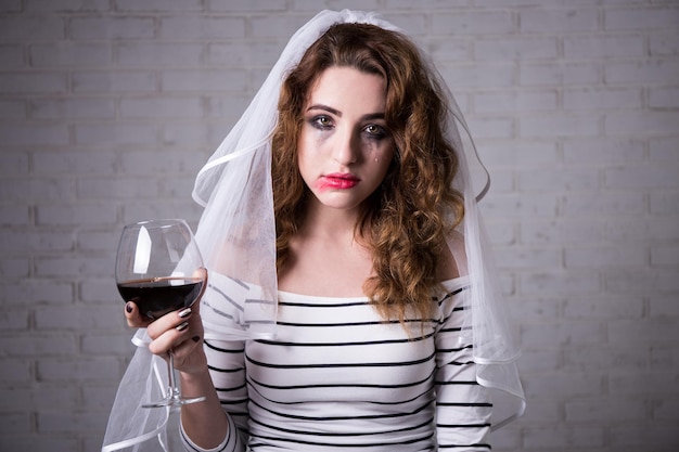 Ritratto di sposa triste che piange e beve vino rosso