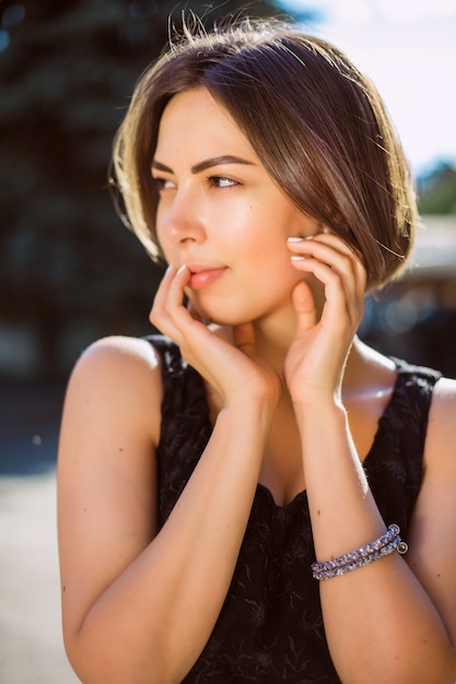 Ritratto di stile di vita di adorabile modella bruna che indossa abiti alla moda, camminando per le strade della città