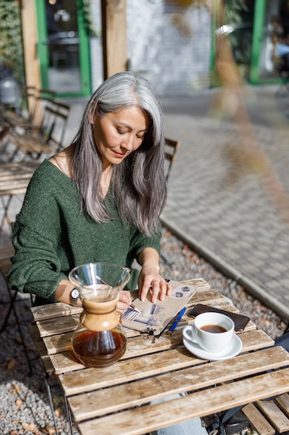 Ritratto di stile di vita di donna elegante capelli pallidi maturi all'aperto vicino a cafe