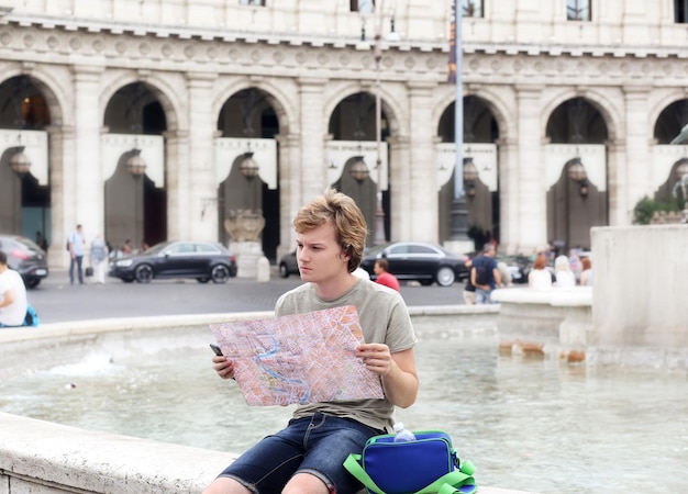 Ritratto di stile di vita di un giovane uomo che si rilassa, un turista che guarda una mappa e usa uno smartphone.