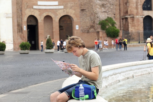 Ritratto di stile di vita di un giovane uomo che si rilassa, un turista che guarda una mappa e usa uno smartphone.