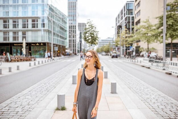 Ritratto di stile di vita di una giovane donna d'affari elegante che cammina per strada nel moderno quartiere degli uffici della città di Amburgo, Germania