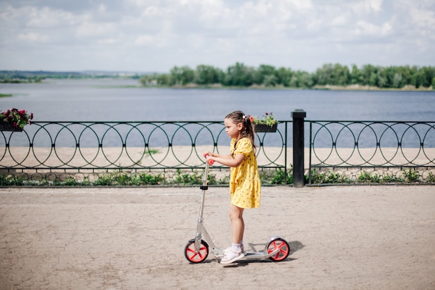 Ritratto di stile di vita il momento del movimento di una ragazza su uno scooter una ragazza in un vestito guida uno scooter