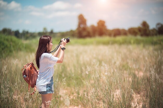 Ritratto di stile di vita sorridente di estate all&#39;aperto di giovane donna graziosa divertendosi con la macchina fotografica