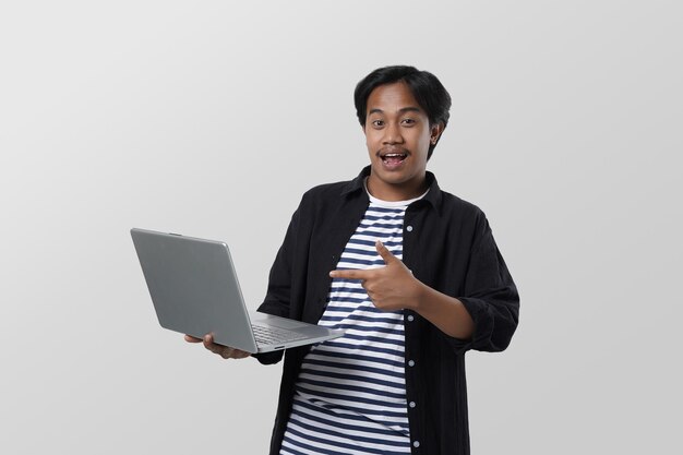 ritratto di studente asiatico intelligente che tiene un laptop in mano con un gesto della mano, guardando la fotocamera