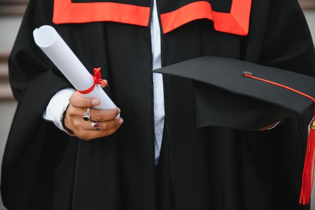 Ritratto di studente indiano di successo in abito di laurea pollice in su