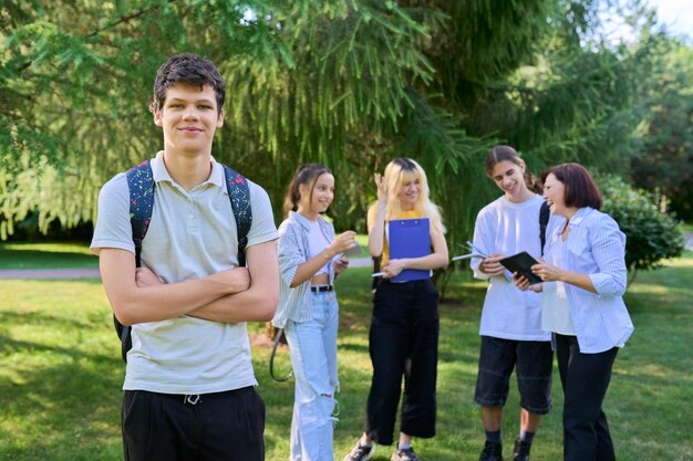 Ritratto di studente maschio nel gruppo del campus del parco di adolescenti con background di insegnante