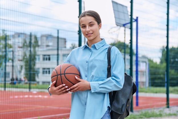 Ritratto di studentessa adolescente con zaino e palla da basket