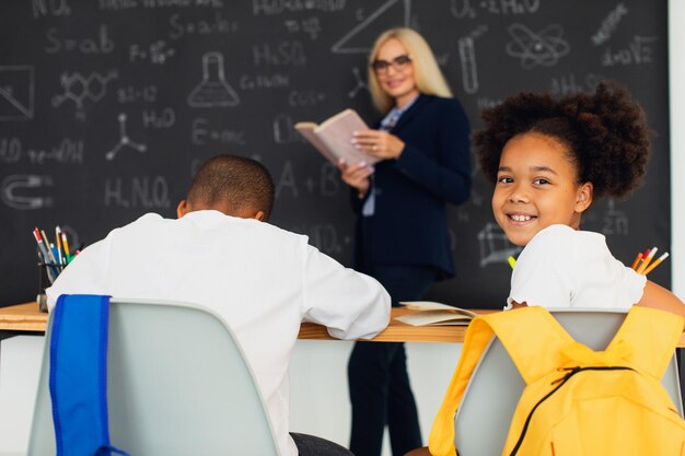 Ritratto di studentessa afroamericana che si siede sullo sfondo dell'aula alla lezione Ritorno a scuola