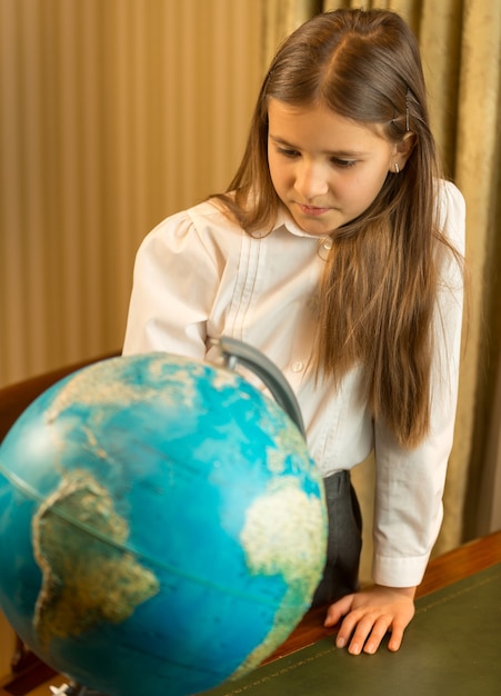 Ritratto di studentessa carina che guarda il globo terrestre