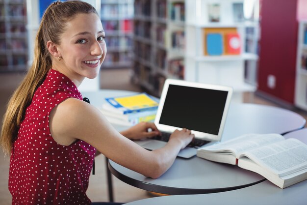 Ritratto di studentessa felice utilizzando laptop in libreria