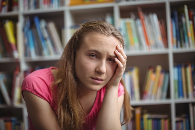 Ritratto di studentessa triste seduto in libreria