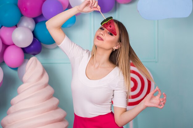 Ritratto di stupefacente donna golosa in abito rosa con caramelle