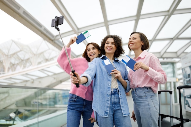 Ritratto di tre donne felici che prendono foto insieme all'aeroporto