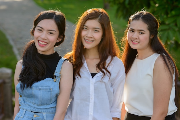 Ritratto di tre giovani donne asiatiche come amici insieme rilassandosi al parco all'aperto
