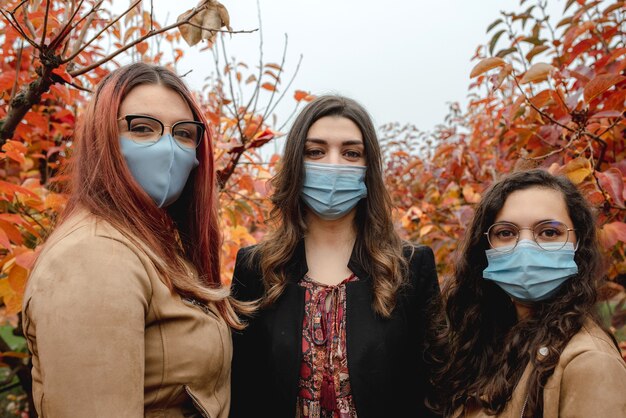 Ritratto di tre ragazze che guardano la telecamera indossando una maschera protettiva per l'infezione da Coronavirus.