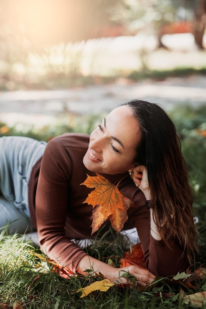 Ritratto di triste bella giovane donna sdraiata sul terreno di una foresta autunnale con foglie di acero colorate Concetto lunedì blu