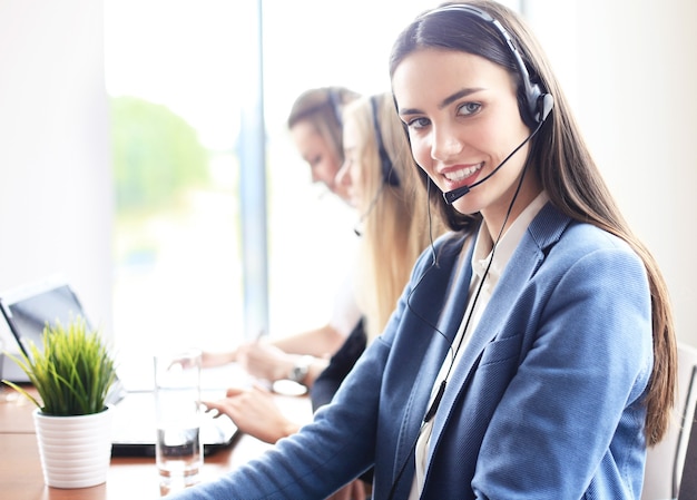 Ritratto di un'addetta al call center accompagnata dal suo team. Operatore di assistenza clienti sorridente al lavoro.